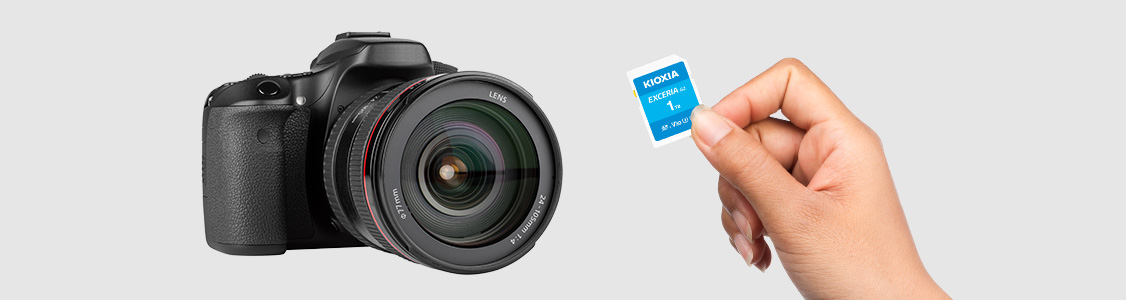 Une carte microSD EXCERIA G2 dans la main devant un appareil photo reflex numérique
